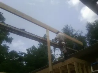 Carpenter setting a ridge beam over a new addition frame — Ice Dam Removal by Roofing Brothers in Mc Cutchenville