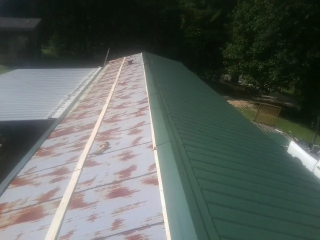 Old rusted panels beside newly installed green metal roofing — Wind Damage Roof Repair by Roofing Brothers in Mc Cutchenville