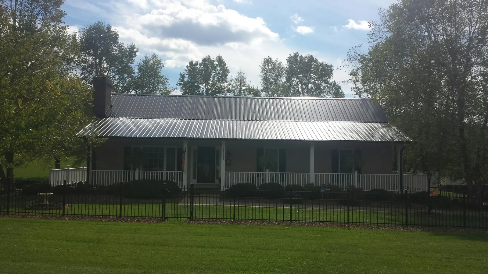 Gray metal roof on a brick ranch with a full width front porch — Gutter Guard Installation work by our crew in Mc Cutchenville