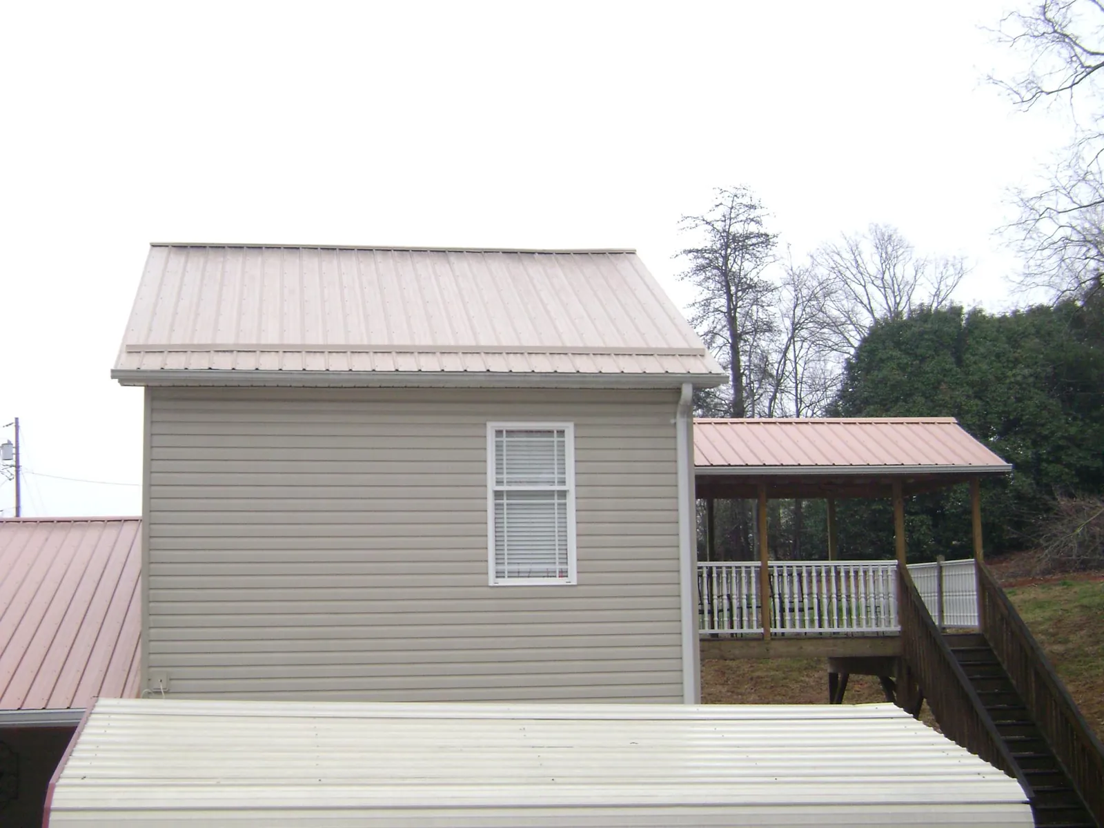 Tan metal roofs on a two story addition and attached porch, from a Roof Replacement job in Mc Cutchenville