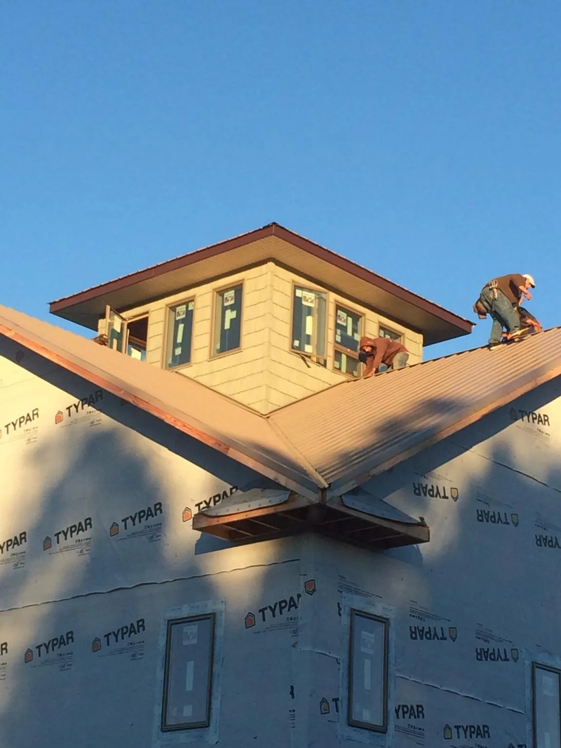 Roofers working around a rooftop cupola on a new metal roof at sunset — Roof Waterproofing in Mc Cutchenville by Roofing Brothers